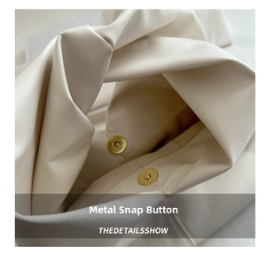 Close-up of golden magnetic snap closure on high-quality white leather handbag detail