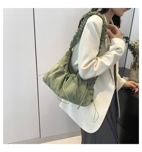 Detailed view of the green pleated tote bag featuring drawstring shoulder strap accents