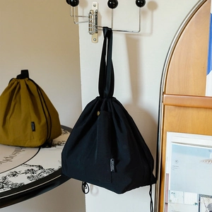 Waterproof drawstring lunch bag in black canvas featuring a side pocket and portable handle