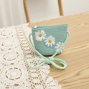 Detail view of a mint green straw bag with white daisy flowers and rope strap