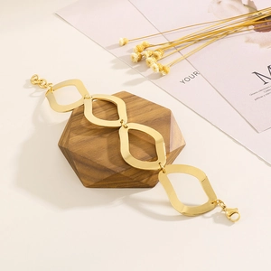 Detail of gold geometric link bracelet on a hexagonal wood block with warm lighting