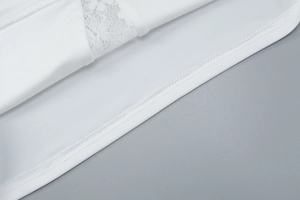Detailed macro view of white lace stitching and precise edge seam on slim t-shirt