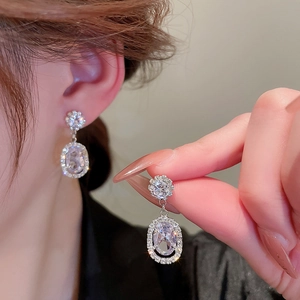Macro shot of silver flower earrings with zircon pendant worn on ear for elegant style