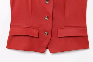 Detail view of dark red vest showing amber buttons and symmetrical flap pockets