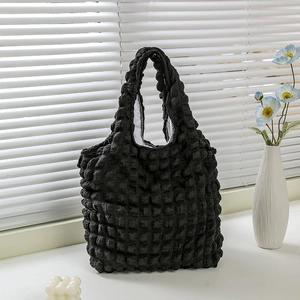 Macro detail of black bubble textured waffle fabric tote bag in minimalist home setting
