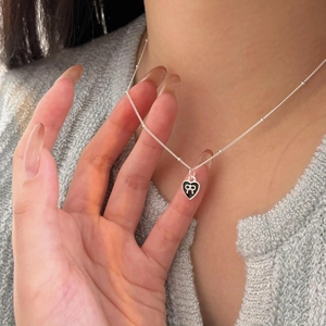 Detail of 925 sterling silver heart necklace with black enamel and silver bow on bead chain