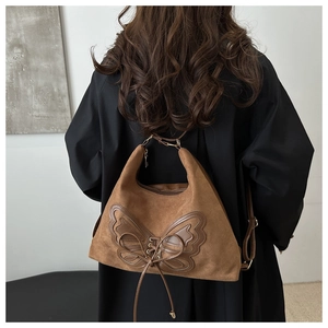 Detail view of a large brown suede tote bag with butterfly leather patch on the back