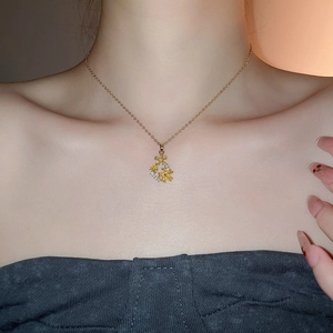 Detail of 18k gold plated flower necklace with yellow gemstone on a model's neck