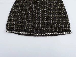 Dettaglio del tessuto tweed nero con fili dorati e raffinata bordatura di perline