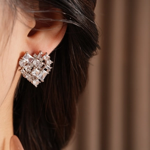 Detailed view of silver heart-shaped stud earring with zircon inlay on female model ear
