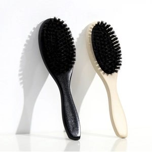 Detail of wooden hairbrushes with black bristles in beige and black colors shown against a wall