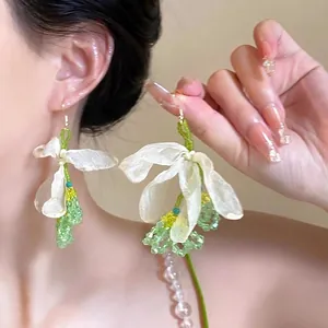 Detail view of handmade satin floral petal drop earrings with green beads and gold hooks