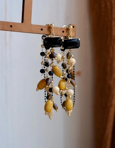 Detail of ethnic style earrings with wooden beads and tassels on a wooden display stand