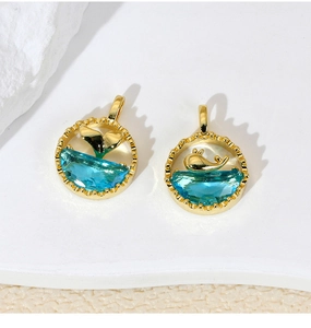 Detailed close-up of gold dolphin tail pendants with blue crystal wave inlays