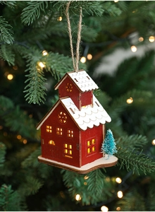 Detail of red and white LED wooden house ornament hanging on a Christmas tree branch