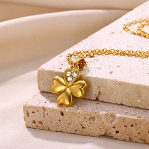 Macro shot of gold four-leaf clover pendant with sparkling white zircons on textured stone