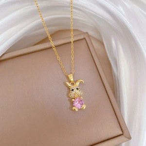 Detail of a golden rabbit necklace with pink center stone and crystal inlay