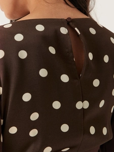 Détail de l'encolure dos avec fermeture à bouton sur une robe marron à pois