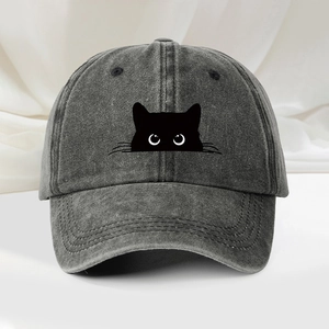 Détail d'une casquette en denim délavé anthracite avec broderie de chat et yeux blancs