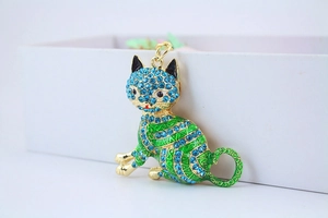 Close-up of golden lucky cat keychain with blue rhinestones and green enamel details