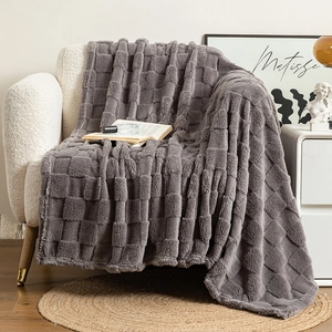Thick dark grey checkered plush blanket draped over a cozy white single sofa in a living room