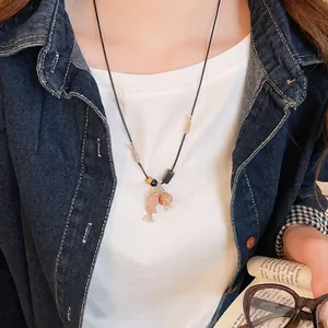 Artistic handmade necklace with wooden fish pendant and tassel worn by a model