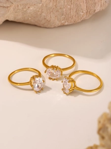 Close-up of three gold rings with large oval clear zircons set on natural stones