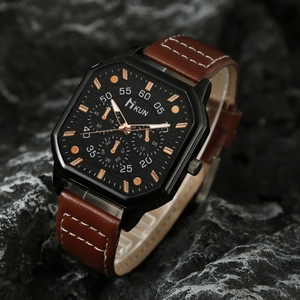 Detail view of square black dial watch with rose gold hands on dark rock surface