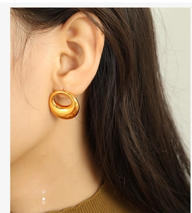 Close-up of chunky gold hoop earrings worn by a model showing a polished metallic finish