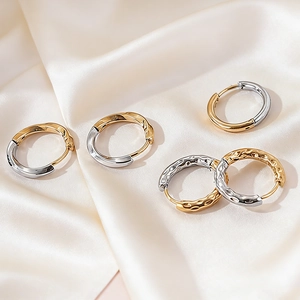 Two-tone titanium steel hoop earrings with hammered texture on beige silk background