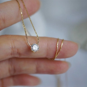 Macro shot of gold snake chain necklace with a brilliant round-cut solitaire zircon pendant