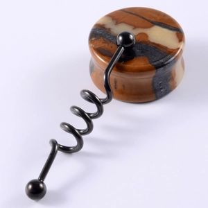 Macro detail of stone resin ear plug disc and black metal spiral piercing accessory