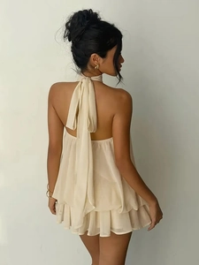 Detail of cream chiffon halter neck dress featuring backless design and ruffled hemline