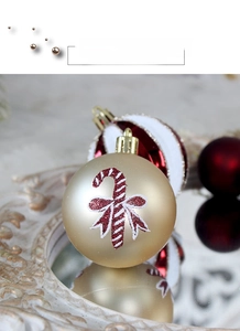 Detailed view of a golden matte Christmas ball with candy cane patterns and a gold hook