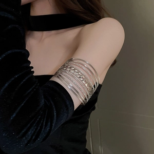 Detail view of multi-layer silver metal arm cuffs with chain texture on model arm