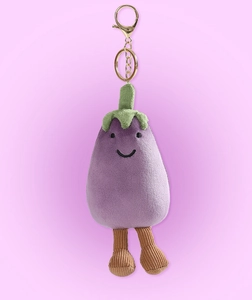 Close-up of cute plush eggplant keychain with corduroy legs and gold metal clip