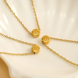 Minimalist gold number pendant necklaces for women in a white decorative shell tray