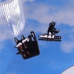 Detailed view of funny black cat enamel pins with knife design on reflective surface