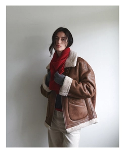 Detail of red wool knit scarf paired with a brown suede jacket and white shearling collar