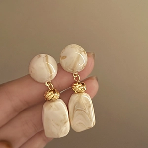 Detailed close-up of geometric marble resin earrings with elegant golden metal links