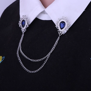 Detail of silver collar brooch with blue pear-shaped gems and double chain on shirt