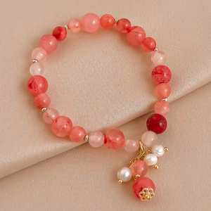 Détail de perles en cristal rose et pompon en perle baroque sur bracelet élastique