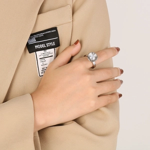 Détail d'une bague multicouche en argent et zircon portée sur un blazer beige chic