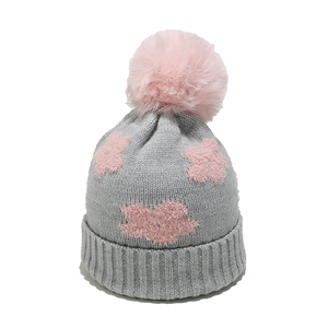 Detail view of grey knitted baby hat with soft pink flower patch and faux fur pompom