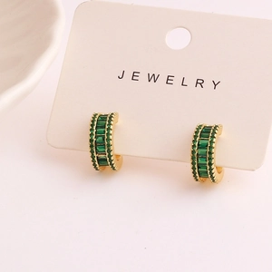 Close-up of C-shaped gold hoop earrings with double-row emerald green crystals