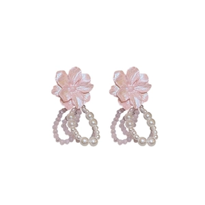 Boucles d'oreilles fleur rose en acrylique avec perles sur un fond blanc épuré
