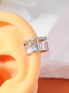 Detailed close-up of a silver ear cuff featuring sparkling circular and baguette zircons