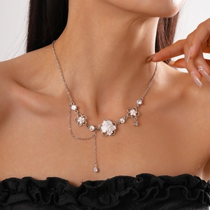 Dettaglio della collana d'argento con ciondolo a fiore di perla e nappa sul décolleté