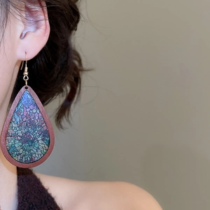 Detail of bohemian wooden teardrop earring with colorful mosaic pattern worn by a model