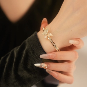 Close-up of gold-plated butterfly bangle with shimmering cubic zirconia on wrist